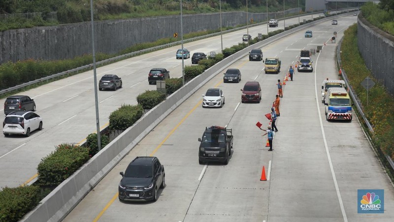 Sejumlah pekerja membersihkan sisa-sisa tanah yang memasuki ruas jalan Tol Serpong - Cinere, Senin (4/11/2024). (CNBC Indonesia/Tri Susilo)