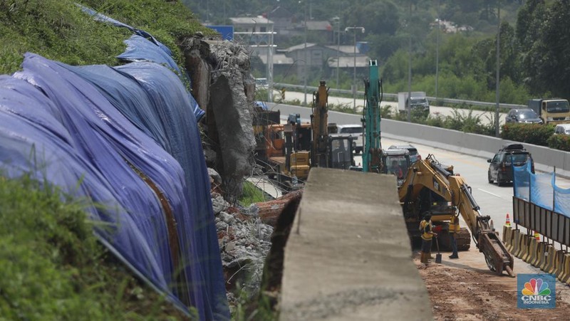 Sejumlah pekerja membersihkan sisa-sisa tanah yang memasuki ruas jalan Tol Serpong - Cinere, Senin (4/11/2024). (CNBC Indonesia/Tri Susilo)