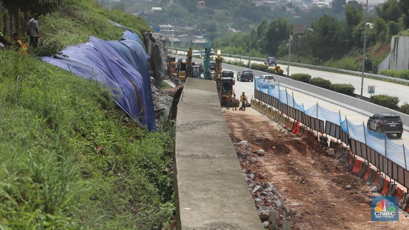 Sejumlah pekerja membersihkan sisa-sisa tanah yang memasuki ruas jalan Tol Serpong - Cinere, Senin (4/11/2024). (CNBC Indonesia/Tri Susilo)