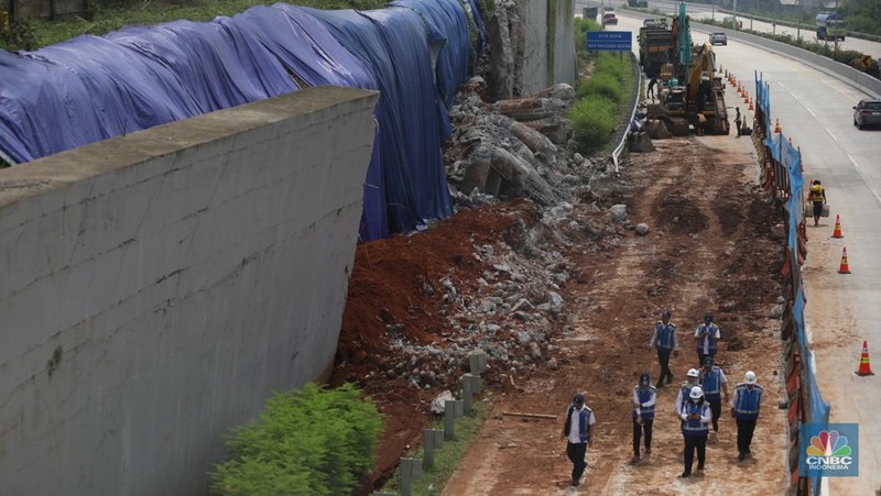 Sejumlah pekerja membersihkan sisa-sisa tanah yang memasuki ruas jalan Tol Serpong - Cinere, Senin (4/11/2024). (CNBC Indonesia/Tri Susilo)