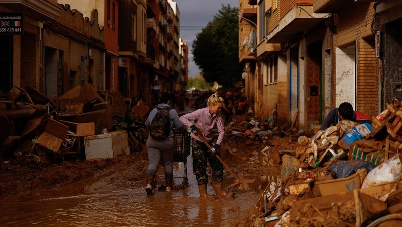 Seorang wanita membersihkan lumpur tebal, akibat banjir akibat hujan lebat, di Sedavi, dekat Valencia, Spanyol, 3 November 2024. (REUTERS/Susana Vera)