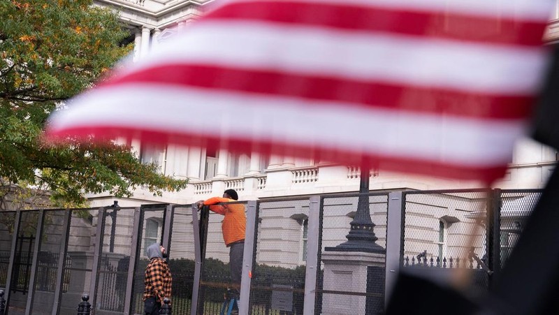 Seorang anggota Dinas Rahasia AS menutup gerbang keamanan di sepanjang Pennsylvania Avenue dekat Gedung Putih pada hari sebelum pemilihan presiden AS di Washington, AS, 4 November 2024. (REUTERS/Nathan Howard)