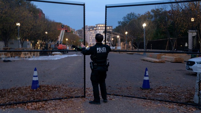 Seorang anggota Dinas Rahasia AS menutup gerbang keamanan di sepanjang Pennsylvania Avenue dekat Gedung Putih pada hari sebelum pemilihan presiden AS di Washington, AS, 4 November 2024. (REUTERS/Nathan Howard)