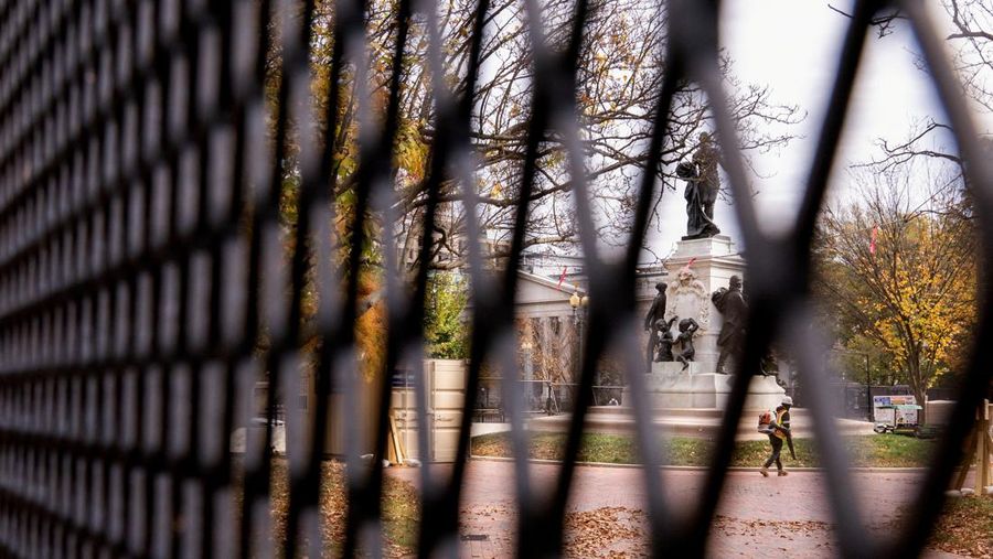 Seorang anggota Dinas Rahasia AS menutup gerbang keamanan di sepanjang Pennsylvania Avenue dekat Gedung Putih pada hari sebelum pemilihan presiden AS di Washington, AS, 4 November 2024. (REUTERS/Nathan Howard)
