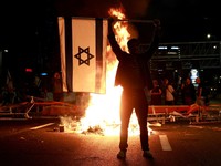Seseorang memegang bendera Israel saat orang-orang berdemonstrasi setelah Perdana Menteri Israel Benjamin Netanyahu memecat menteri pertahanannya, Yoav Gallant, dengan alasan kurangnya kepercayaan, di Tel Aviv, Israel, 5 November 2024. (REUTERS/Ammar