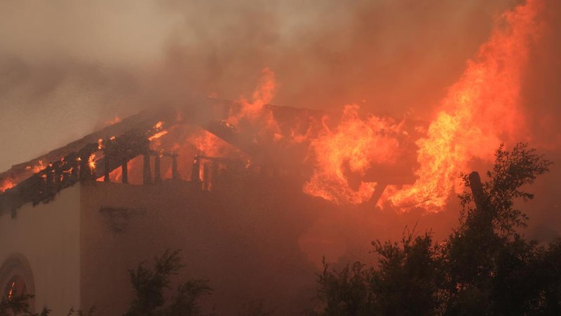 Pemandangan menunjukkan properti yang rusak terbakar, sementara asap mengepul dari Kebakaran Gunung di Camarillo, California, AS, 6 November 2024. (REUTERS/David Swanson)