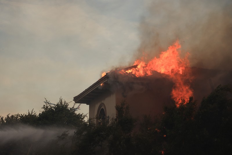 Pemandangan menunjukkan properti yang rusak terbakar, sementara asap mengepul dari Kebakaran Gunung di Camarillo, California, AS, 6 November 2024. Pemandangan menunjukkan properti yang rusak terbakar, sementara asap mengepul dari Kebakaran Gunung di Camarillo, California, AS, 6 November 2024. (REUTERS/David Swanson)