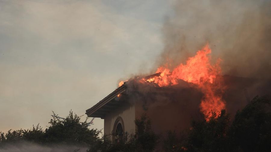 Pemandangan menunjukkan properti yang rusak terbakar, sementara asap mengepul dari Kebakaran Gunung di Camarillo, California, AS, 6 November 2024. (REUTERS/David Swanson)