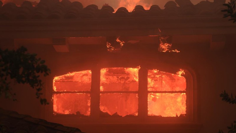 Pemandangan menunjukkan properti yang rusak terbakar, sementara asap mengepul dari Kebakaran Gunung di Camarillo, California, AS, 6 November 2024. (REUTERS/David Swanson)