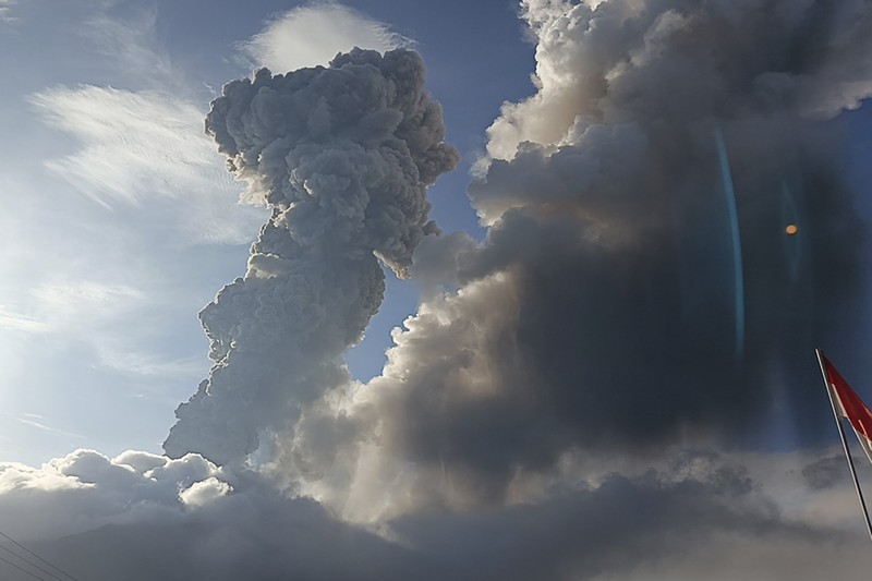 Warga berkendara dengan latar belakang Gunung Lewotobi Laki Laki memuntahkan material vulkanik saat terjadi letusan di Flores Timur, Indonesia, Sabtu, 9 November 2024.(Photo by ARNOLD WELIANTO / AFP) Warga berkendara dengan latar belakang Gunung Lewotobi Laki Laki memuntahkan material vulkanik saat terjadi letusan di Flores Timur, Indonesia, Sabtu, 9 November 2024.(Photo by ARNOLD WELIANTO / AFP)
