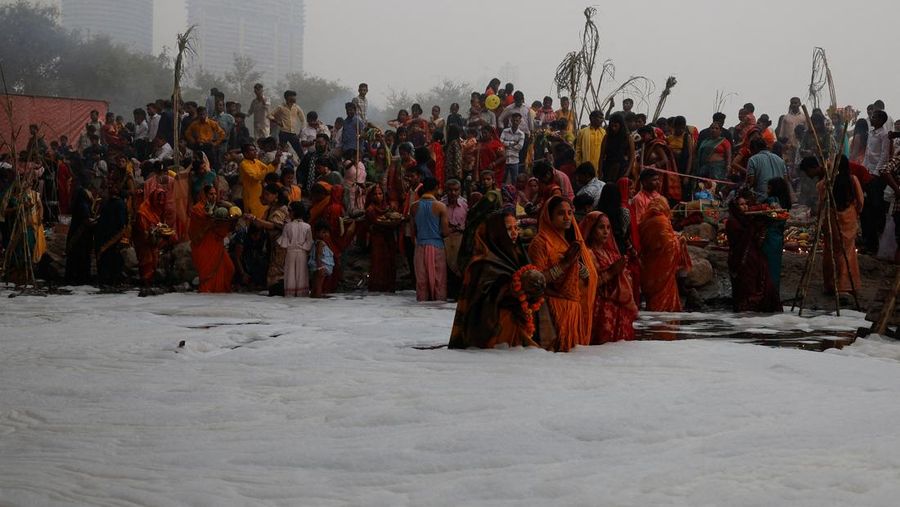 Festival keagamaan Hindu Chhath Puja tetap berlangsung khidmat meski buih-buih limbah menutupi Sungai Yamuna, New Delhi, India, Kamis (7/11). (REUTERS/Anushree Fadnavis)