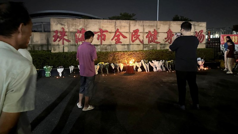 Orang-orang membakar dupa di dekat karangan bunga di luar pusat olahraga tempat serangan tabrak lari mematikan terjadi, di Zhuhai, Guangdong, China, (12/11/2024). (REUTERS/Tingshu Wang)