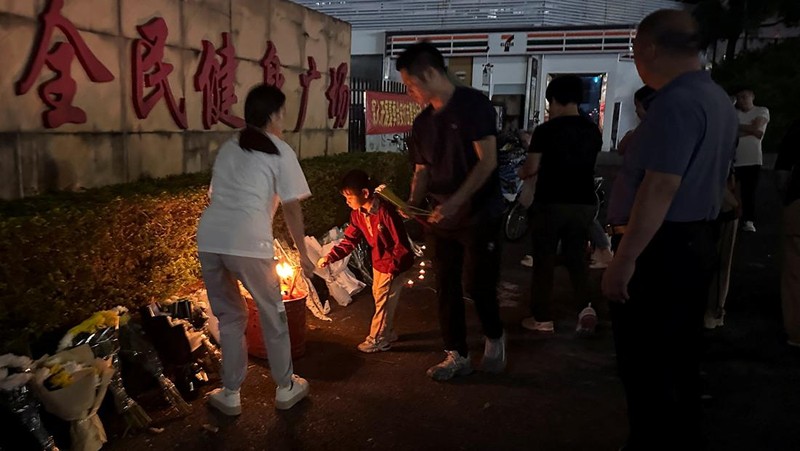 Orang-orang membakar dupa di dekat karangan bunga di luar pusat olahraga tempat serangan tabrak lari mematikan terjadi, di Zhuhai, Guangdong, China, (12/11/2024). (REUTERS/Tingshu Wang)