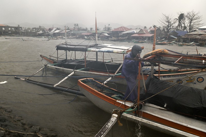 Seorang pria mendorong sepeda motornya di tengah hujan lebat akibat Topan Usagi di Santa Ana, provinsi Cagayan, Filipina utara pada Kamis, 14 November 2024. (AP Photo/Noel Celis)