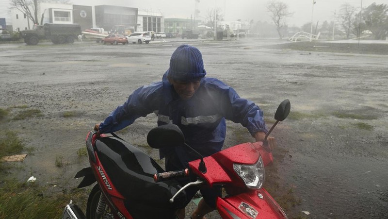 Seorang pria mendorong sepeda motornya di tengah hujan lebat akibat Topan Usagi di Santa Ana, provinsi Cagayan, Filipina utara pada Kamis, 14 November 2024. (AP Photo/Noel Celis)