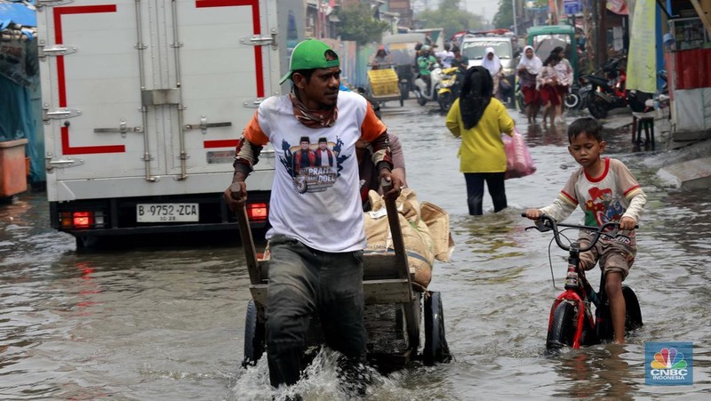 Sejumlah warga beraktivitas di wilayah yang tergenang rob di Penjaringan, Jakarta Utara, Jumat (15/11/2024). (CNBC Indonesia/Muhammad Sabki)