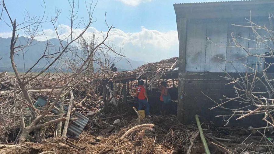 Warga berjalan di atas kayu gelondongan dan puing-puing yang tersapu banjir akibat Topan Usagi di Gonzaga, provinsi Cagayan, Filipina utara, Jumat (15/11/2024). (AP Photo/Noel Celis)