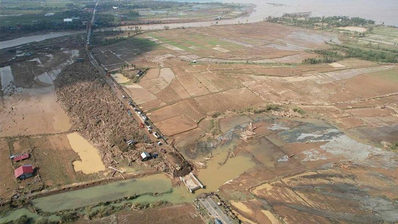 Warga berjalan di atas kayu gelondongan dan puing-puing yang tersapu banjir akibat Topan Usagi di Gonzaga, provinsi Cagayan, Filipina utara, Jumat (15/11/2024). (AP Photo/Noel Celis)