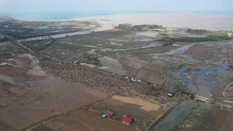 Warga berjalan di atas kayu gelondongan dan puing-puing yang tersapu banjir akibat Topan Usagi di Gonzaga, provinsi Cagayan, Filipina utara, Jumat (15/11/2024). (AP Photo/Noel Celis)