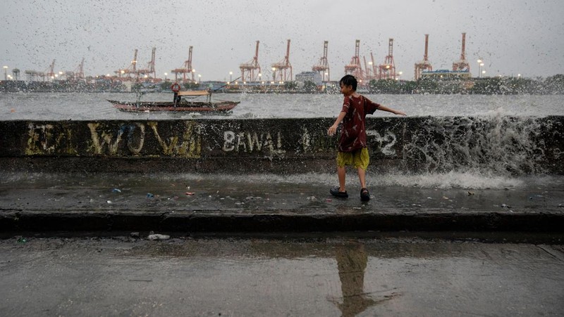 Anak-anak bermain di dekat ombak kencang dari Sungai Pasig di tengah Topan Hebat Man-yi, di Manila, Filipina, 17 November 2024. (REUTERS/Lisa Marie David)