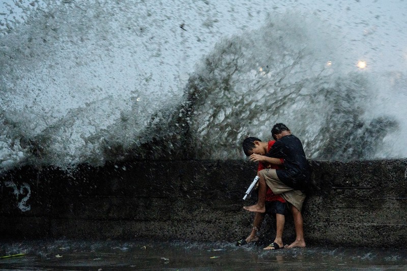 Anak-anak bermain di dekat ombak kencang dari Sungai Pasig di tengah Topan Hebat Man-yi, di Manila, Filipina, 17 November 2024. (REUTERS/Lisa Marie David)