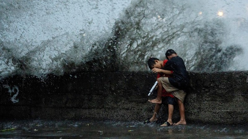 Anak-anak bermain di dekat ombak kencang dari Sungai Pasig di tengah Topan Hebat Man-yi, di Manila, Filipina, 17 November 2024. (REUTERS/Lisa Marie David)