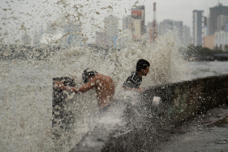 Anak-anak bermain di dekat ombak kencang dari Sungai Pasig di tengah Topan Hebat Man-yi, di Manila, Filipina, 17 November 2024. (REUTERS/Lisa Marie David)