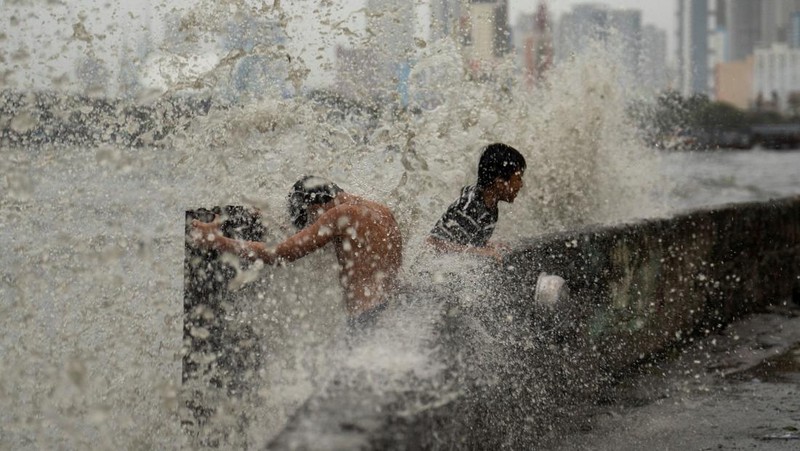 Anak-anak bermain di dekat ombak kencang dari Sungai Pasig di tengah Topan Hebat Man-yi, di Manila, Filipina, 17 November 2024. (REUTERS/Lisa Marie David)