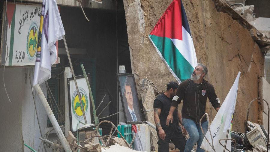 Orang-orang berdiri di atas reruntuhan setelah serangan Israel terhadap sebuah gedung yang menurut sumber keamanan menewaskan kepala hubungan media Hizbullah Mohammad Afif di Ras Al-Nabaa, di Beirut, Lebanon, 17 November 2024. (REUTERS/Adnan Abidi)