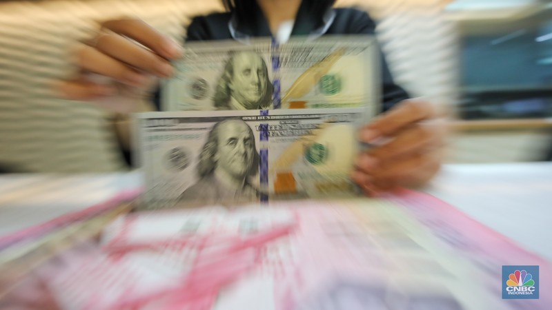 Petugas menunjukkan uang pecahan dolar AS dan rupiah di gerai penukaran mata uang asing di tempat penukaran uang PT Ayu Masagung, Jakarta, Senin (18/11/2024). (CNBC Indonesia/Faisal Rahman) Petugas menunjukkan uang pecahan dolar AS dan rupiah di gerai penukaran mata uang asing di tempat penukaran uang PT Ayu Masagung, Jakarta, Senin (18/11/2024). (CNBC Indonesia/Faisal Rahman)