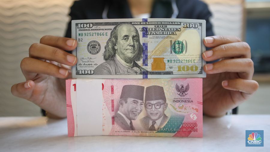 Petugas menunjukkan uang pecahan dolar AS dan rupiah di gerai penukaran mata uang asing di tempat penukaran uang PT Ayu Masagung, Jakarta, Senin (18/11/2024). (CNBC Indonesia/Faisal Rahman)