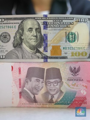 Petugas menunjukkan uang pecahan dolar AS dan rupiah di gerai penukaran mata uang asing di tempat penukaran uang PT Ayu Masagung, Jakarta, Senin (18/11/2024). (CNBC Indonesia/Faisal Rahman)