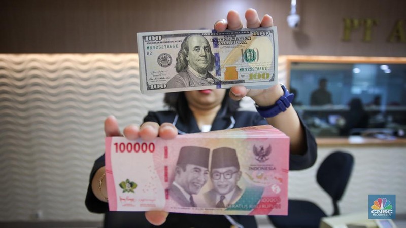 Petugas menunjukkan uang pecahan dolar AS dan rupiah di gerai penukaran mata uang asing di tempat penukaran uang PT Ayu Masagung, Jakarta, Senin (18/11/2024). (CNBC Indonesia/Faisal Rahman)