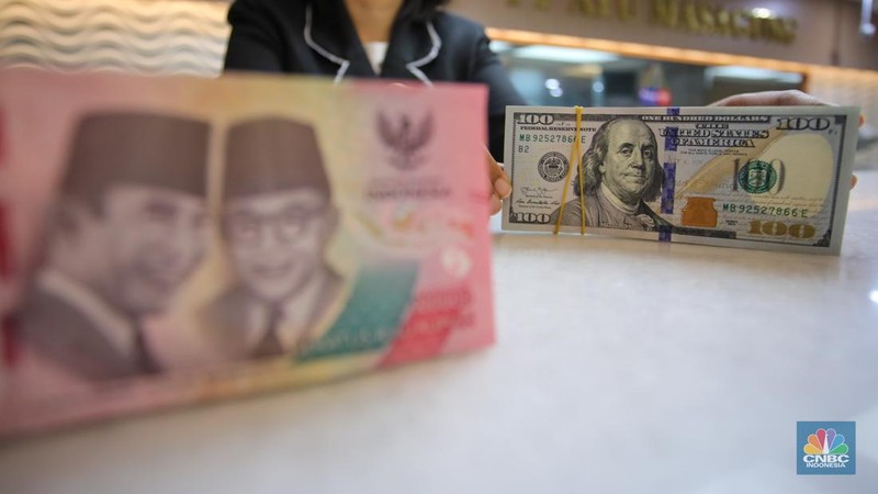 Petugas menunjukkan uang pecahan dolar AS dan rupiah di gerai penukaran mata uang asing di tempat penukaran uang PT Ayu Masagung, Jakarta, Senin (18/11/2024). (CNBC Indonesia/Faisal Rahman)