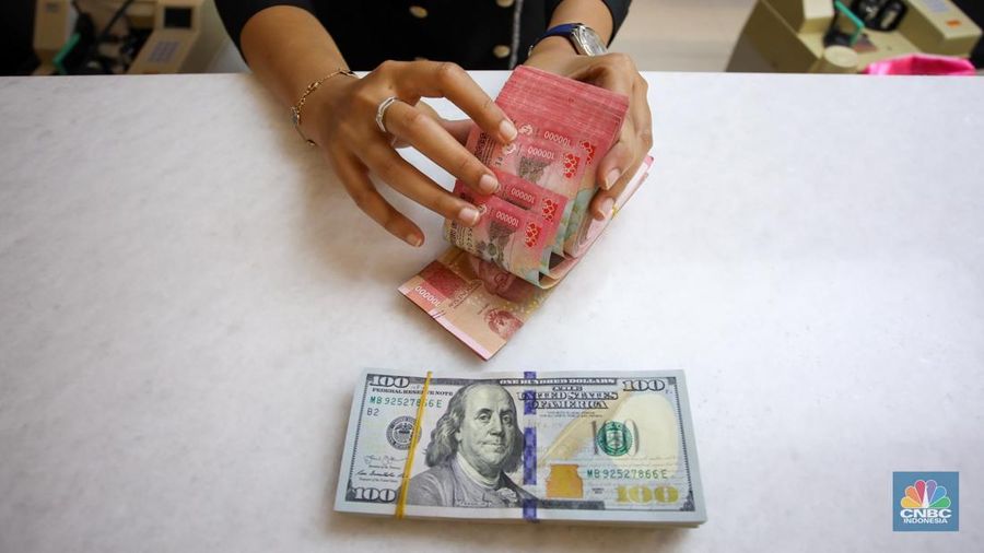 Petugas menunjukkan uang pecahan dolar AS dan rupiah di gerai penukaran mata uang asing di tempat penukaran uang PT Ayu Masagung, Jakarta, Senin (18/11/2024). (CNBC Indonesia/Faisal Rahman)