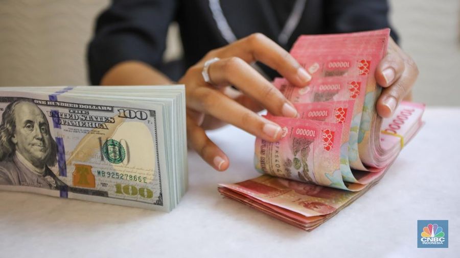 Petugas menunjukkan uang pecahan dolar AS dan rupiah di gerai penukaran mata uang asing di tempat penukaran uang PT Ayu Masagung, Jakarta, Senin (18/11/2024). (CNBC Indonesia/Faisal Rahman)