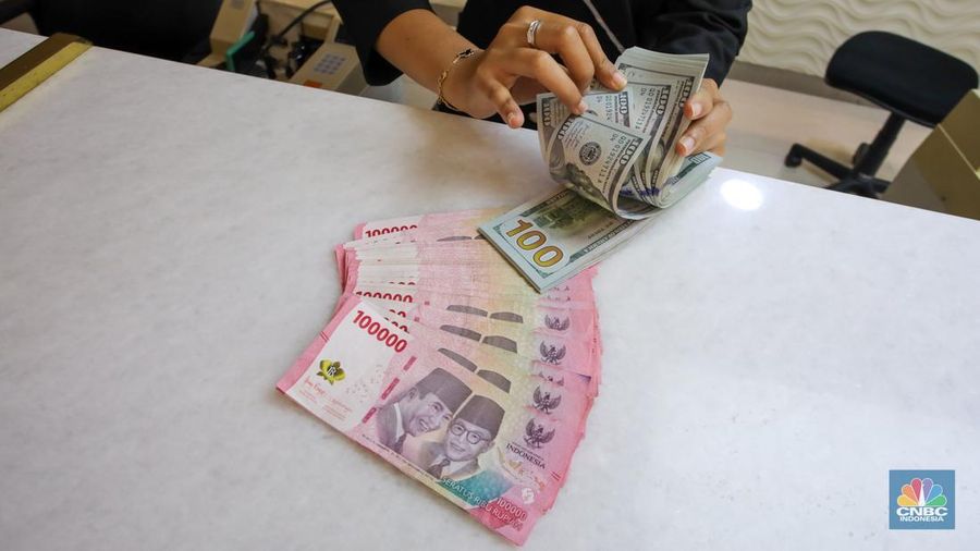 Petugas menunjukkan uang pecahan dolar AS dan rupiah di gerai penukaran mata uang asing di tempat penukaran uang PT Ayu Masagung, Jakarta, Senin (18/11/2024). (CNBC Indonesia/Faisal Rahman)