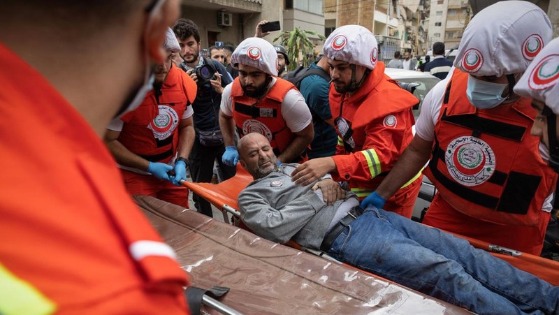 Orang-orang dan tim penyelamat berkumpul di lokasi serangan Israel terhadap sebuah gedung yang menurut sumber keamanan menewaskan kepala hubungan media Hizbullah Mohammad Afif di Ras Al-Nabaa, di Beirut, Lebanon, 17 November 2024. (REUTERS/Adnan Abidi)