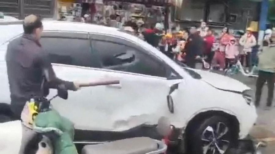 Seorang pria memecahkan kaca mobil setelah tabrakan kendaraan di luar sebuah sekolah dasar di Changde, provinsi Hunan, China dalam tangkapan layar yang diperoleh dari video media sosial yang dirilis pada 19 November 2024. (Social Media/via REUTERS)
