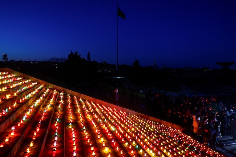 Warga Kota Kyiv, Ukraina, menggelar acara khusus untuk memperingati 1.000 hari sejak invasi besar-besaran Rusia dimulai pada 24 Februari 2022. Dalam peringatan ini, mereka menyalakan seribu lilin dan berdoa di depan Monumen Ibu Pertiwi. (REUTERS/Valentyn Ogirenko)