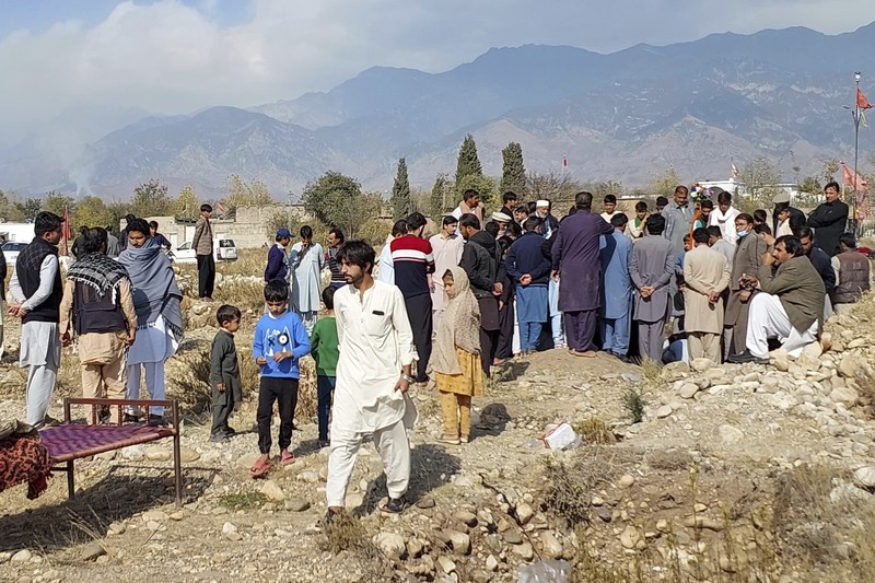Seorang pelayat berdiri di samping jenazah para korban yang tewas dalam insiden penembakan oleh pria bersenjata, sebelum salat jenazah mereka, di Parachinar, kota utama distrik Kurram di provinsi Khyber Pakhtunkhwa, barat laut Pakistan, Jumat, 22 November 2024. (AP Photo/Hussain Ali)