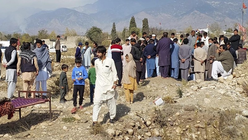 Seorang pelayat berdiri di samping jenazah para korban yang tewas dalam insiden penembakan oleh pria bersenjata, sebelum salat jenazah mereka, di Parachinar, kota utama distrik Kurram di provinsi Khyber Pakhtunkhwa, barat laut Pakistan, Jumat, 22 November 2024. (AP Photo/Hussain Ali)