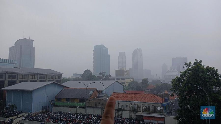 Pekerja mengamati curah hujan yang cukup deras di kawasan perkantoran wilayah Jakarta, Jumat (22/11/2024). (CNBC Indonesia/Tri Susilo)
