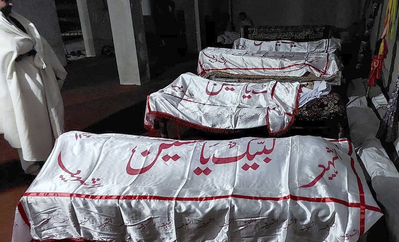 Seorang pelayat berdiri di samping jenazah para korban yang tewas dalam insiden penembakan oleh pria bersenjata, sebelum salat jenazah mereka, di Parachinar, kota utama distrik Kurram di provinsi Khyber Pakhtunkhwa, barat laut Pakistan, Jumat, 22 November 2024. (AP Photo/Hussain Ali)
