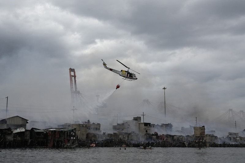 Philippines Fire A Philippine Air Force helicopter drops water on burning homes as fire broke out at a slum area leaving about 2,000 families homeless on Sunday, Nov. 24, 2024 in Manila, Philippines. (AP Photo/Aaron Favila)