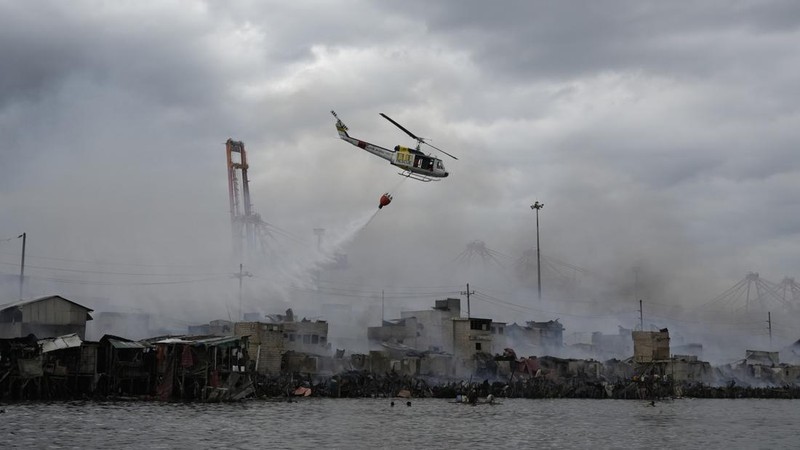 A Philippine Air Force helicopter drops water on burning homes as fire broke out at a slum area leaving about 2,000 families homeless on Sunday, Nov. 24, 2024 in Manila, Philippines. (AP Photo/Aaron Favila)