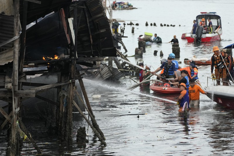 A Philippine Air Force helicopter drops water on burning homes as fire broke out at a slum area leaving about 2,000 families homeless on Sunday, Nov. 24, 2024 in Manila, Philippines. (AP Photo/Aaron Favila)