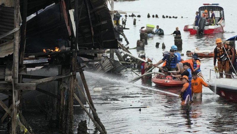 A Philippine Air Force helicopter drops water on burning homes as fire broke out at a slum area leaving about 2,000 families homeless on Sunday, Nov. 24, 2024 in Manila, Philippines. (AP Photo/Aaron Favila)