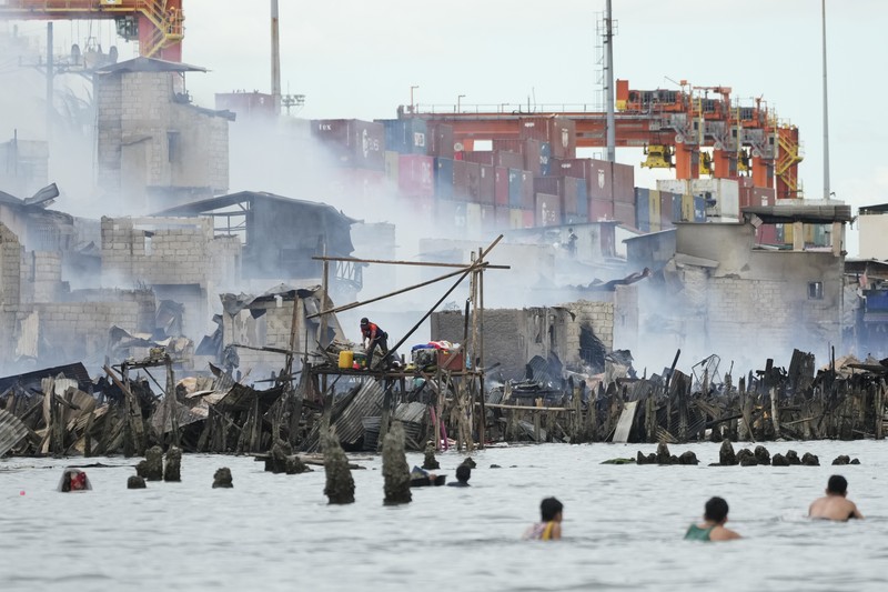 A Philippine Air Force helicopter drops water on burning homes as fire broke out at a slum area leaving about 2,000 families homeless on Sunday, Nov. 24, 2024 in Manila, Philippines. (AP Photo/Aaron Favila)