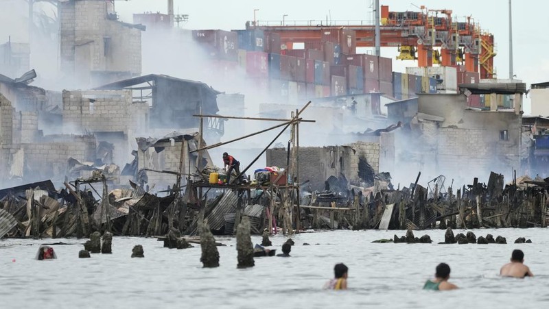 A Philippine Air Force helicopter drops water on burning homes as fire broke out at a slum area leaving about 2,000 families homeless on Sunday, Nov. 24, 2024 in Manila, Philippines. (AP Photo/Aaron Favila)